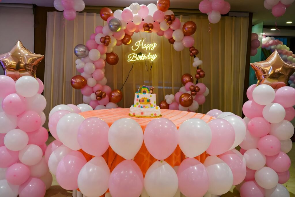 Pink and white balloon arch over a birthday dessert table
