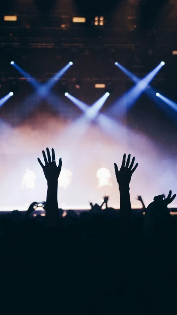 Fans with raised hands under concert lights