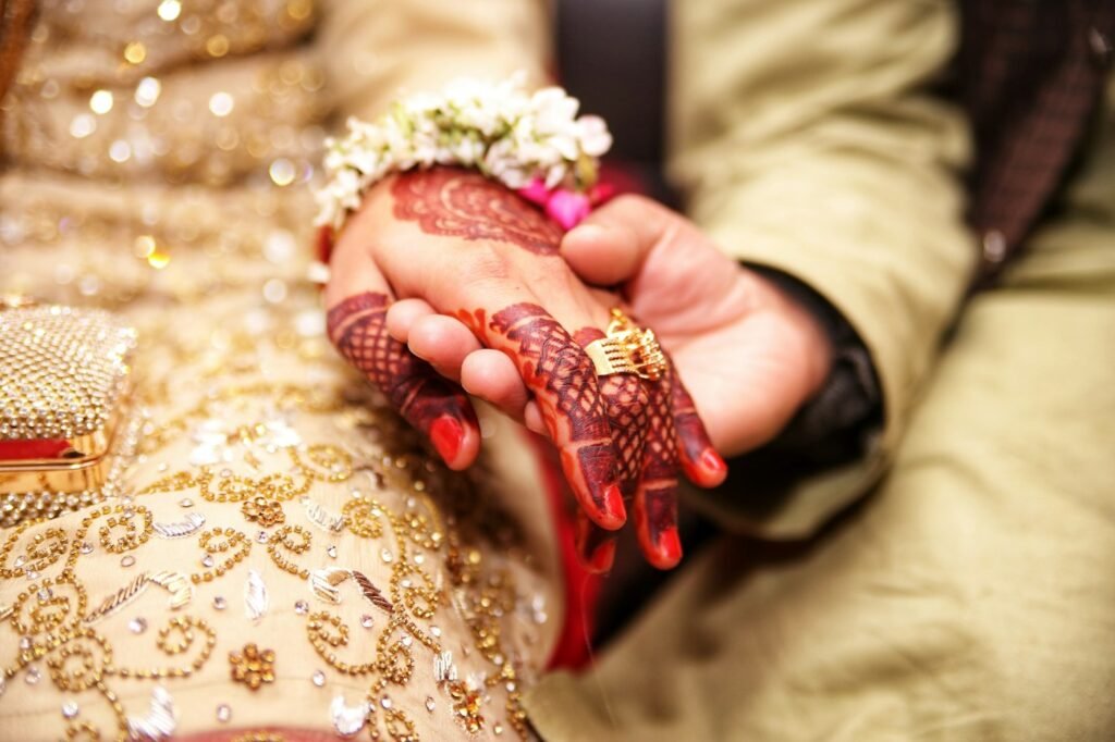 Hennaed hand with a gold ring held in the groom's hand